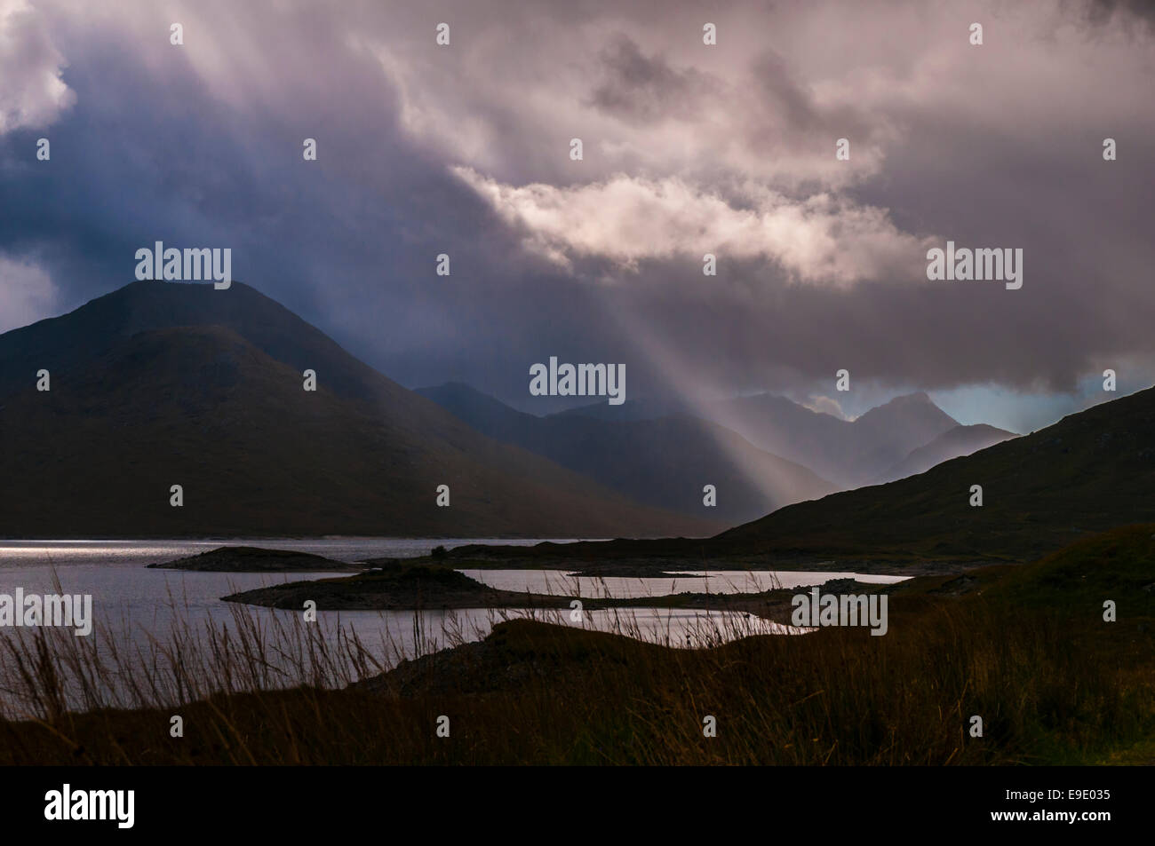 Wild atmosphere with Crepuscular rays through Storm clouds on Loch Quoich, Lochaber, Highlands, Scotland. Stock Photo