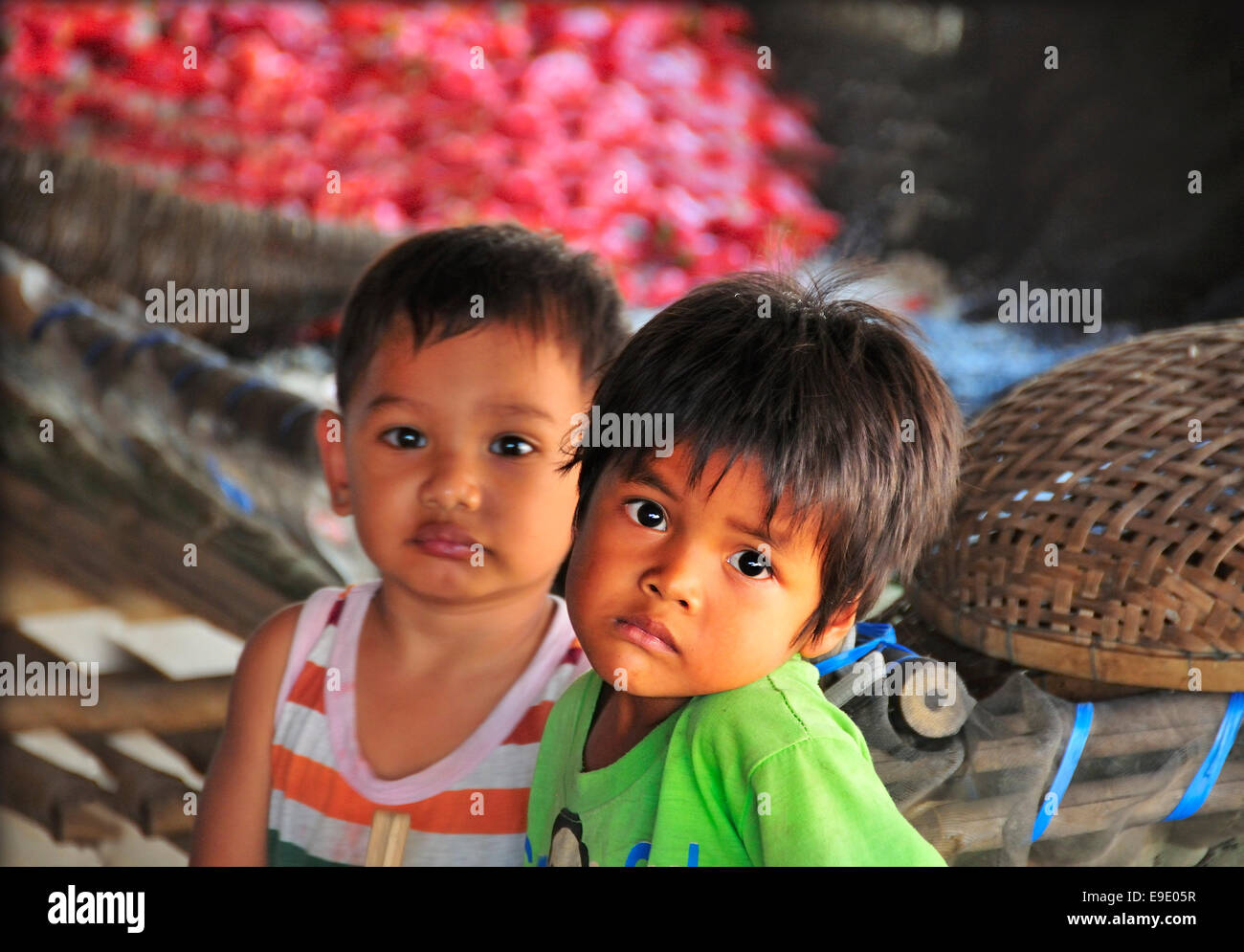 Two young Cambodian  boys having to wait while their mothers worked sorting and drying red peppers in Cambodia Stock Photo