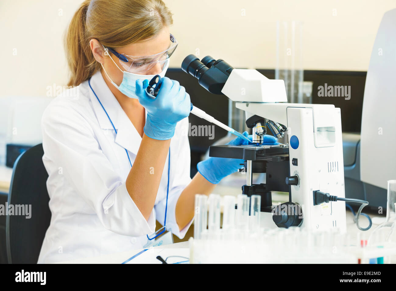 Beautiful woman in a laboratory working with a microscope. Stock Photo