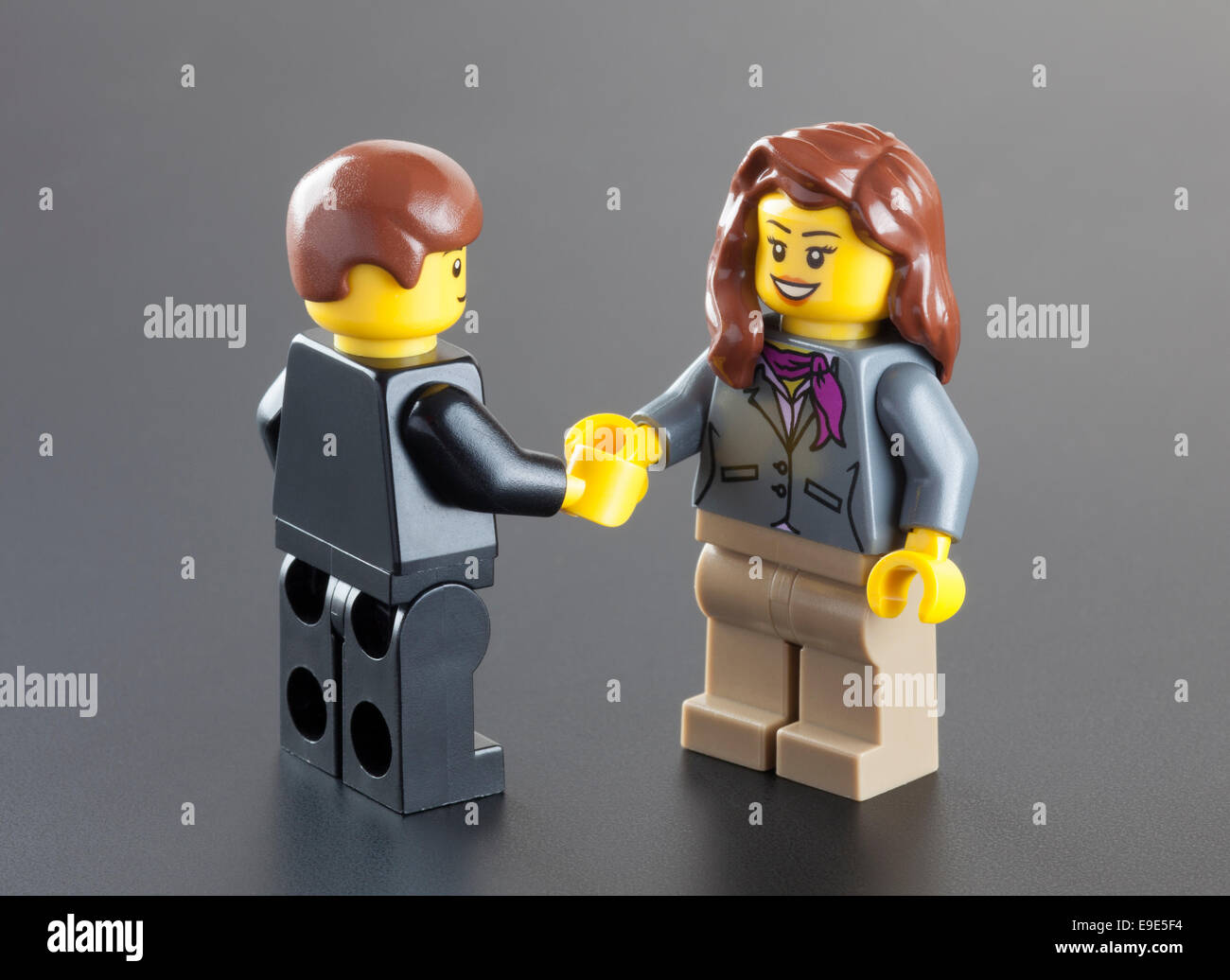 Tambov, Russian Federation - October 04, 2013 Lego minifigures businessman and businesswoman shaking hands on black background. Stock Photo