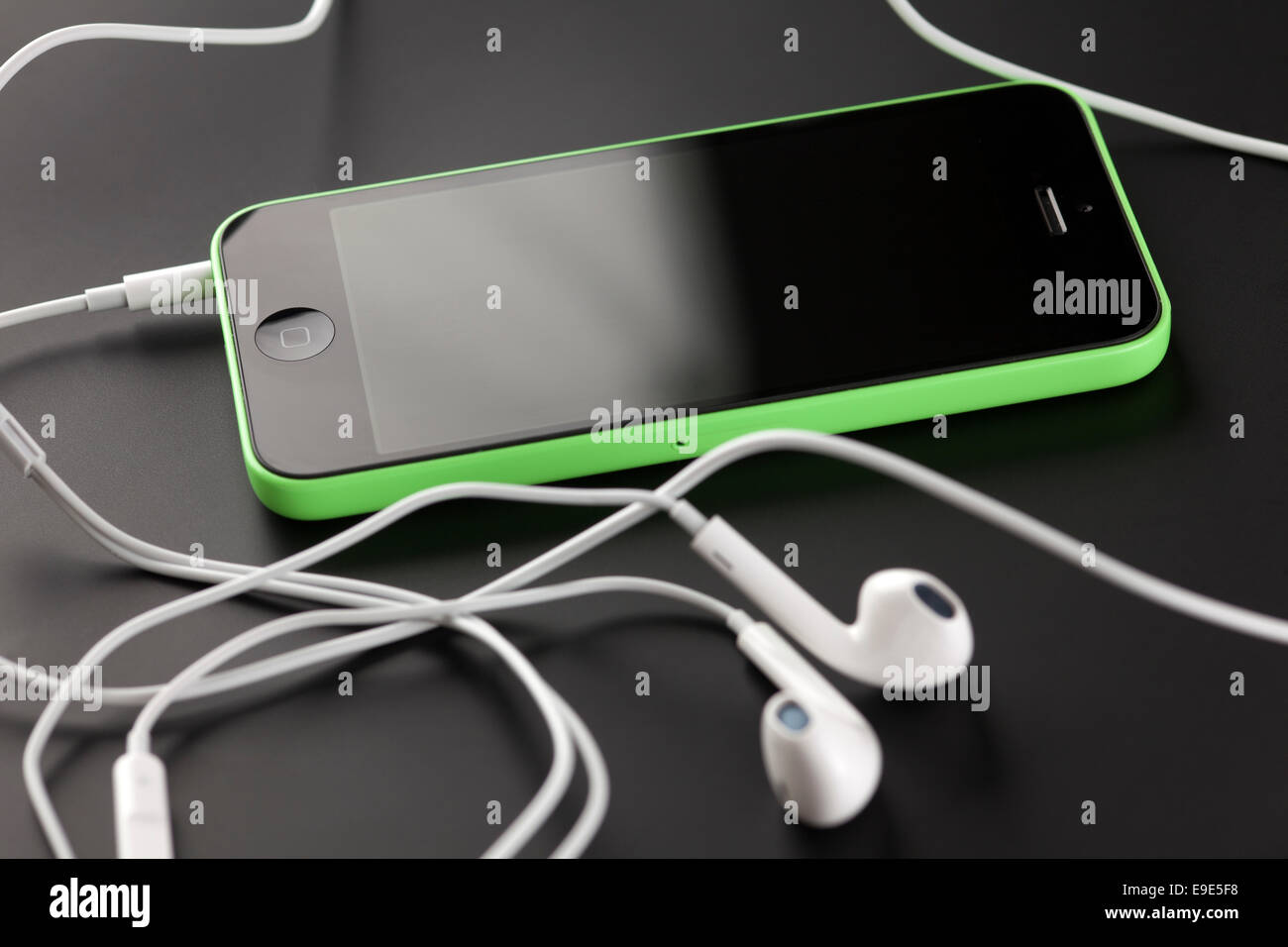 Tambov, Russian Federation - October 16, 2013: Apple iPhone 5C Green Color, Apple EarPods on black background. Stock Photo