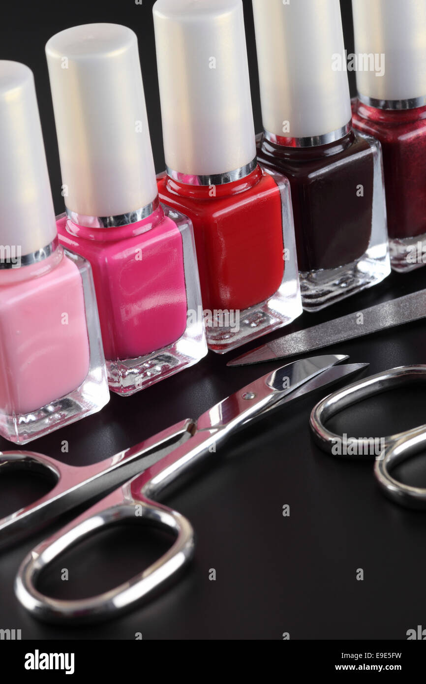 Nail polishes in a row and manicure set on black background Stock Photo ...