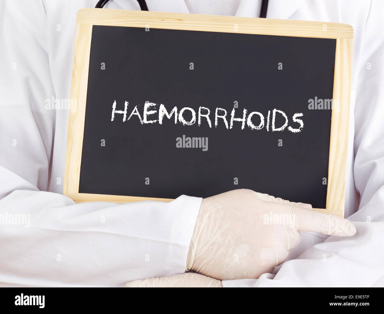 Doctor shows information on blackboard: haemorrhoids Stock Photo