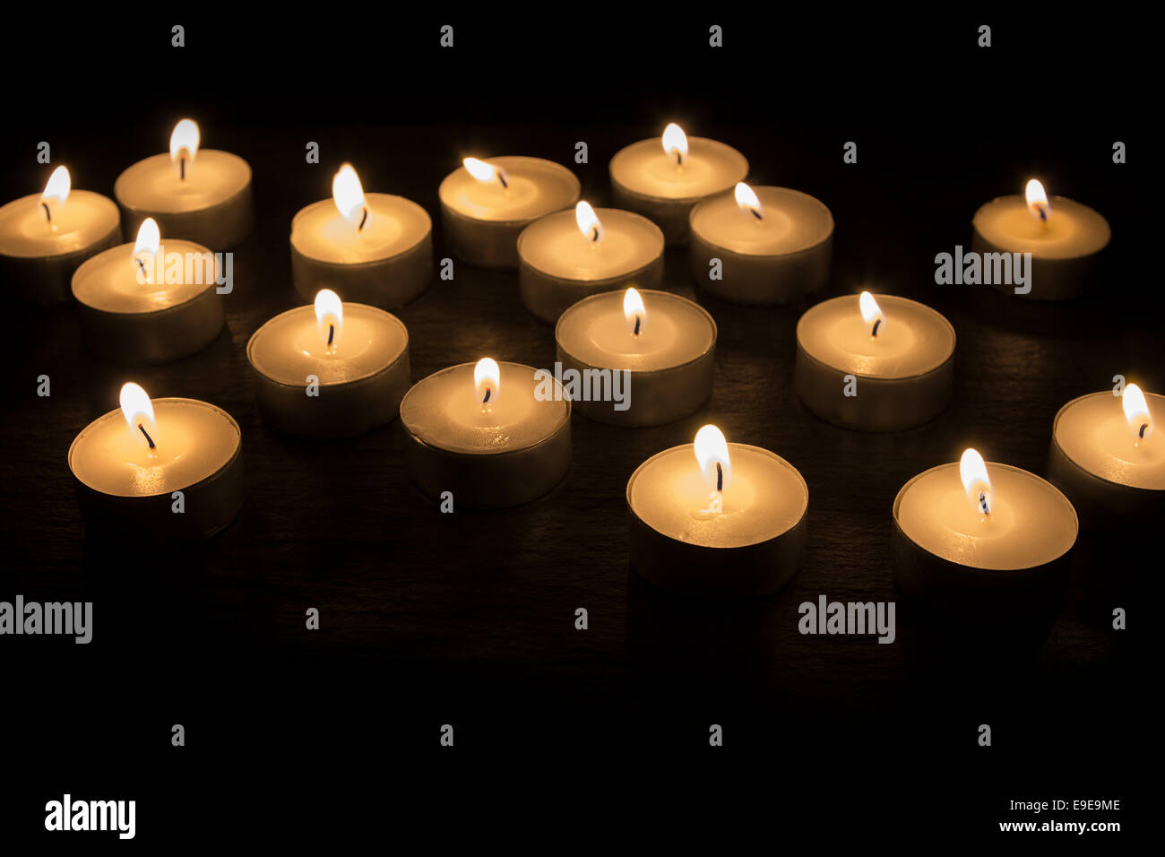 A Group of tea candles burning on a black background Stock Photo Alamy