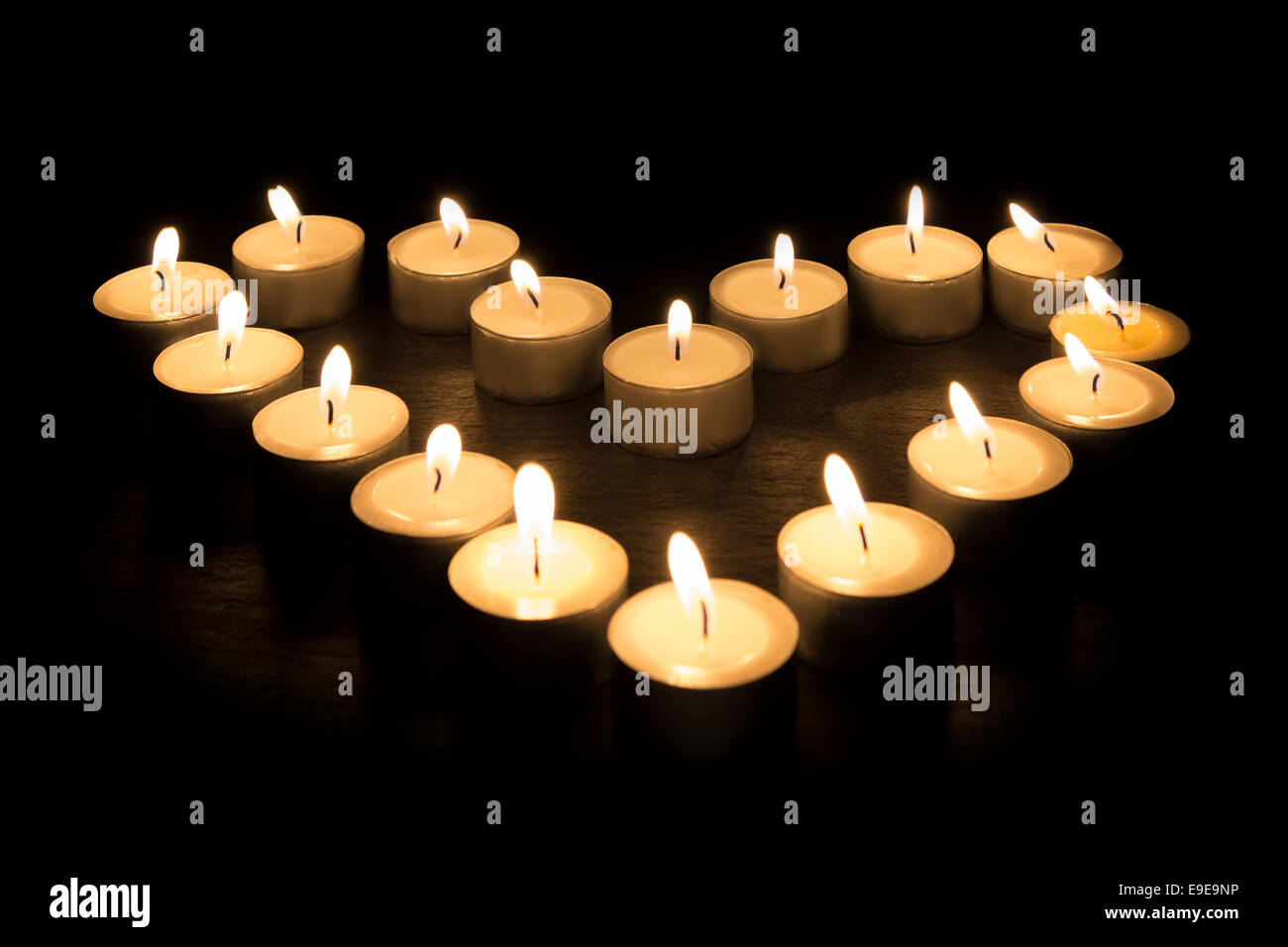 Tea Candles forming a heart shape on black background Stock Photo Alamy