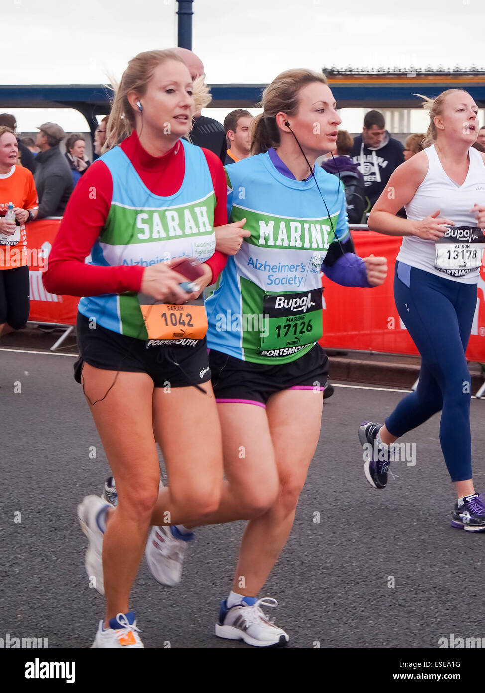 Portsmouth, UK. 26th October 2014. A female runner assists her friend across the finishing line as 25000 runners take part in the Great South run. The run consists of  a 10 mile road race through the streets of Portsmouth. Credit:  simon evans/Alamy Live News Stock Photo