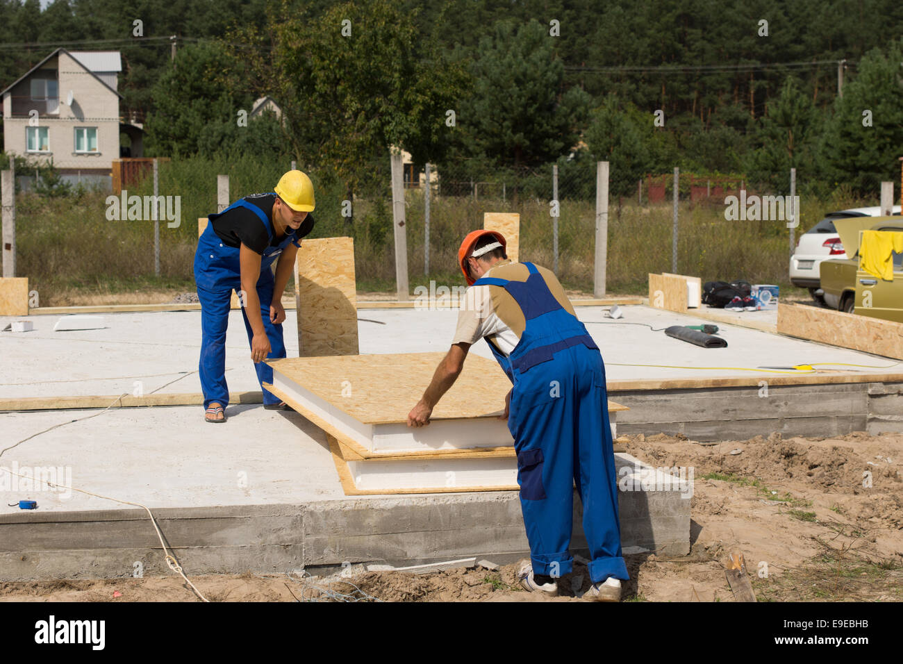 Two builders or construction workers handling insulated wall panels as they get ready to install them on the floor and foundation of a new build house. Stock Photo