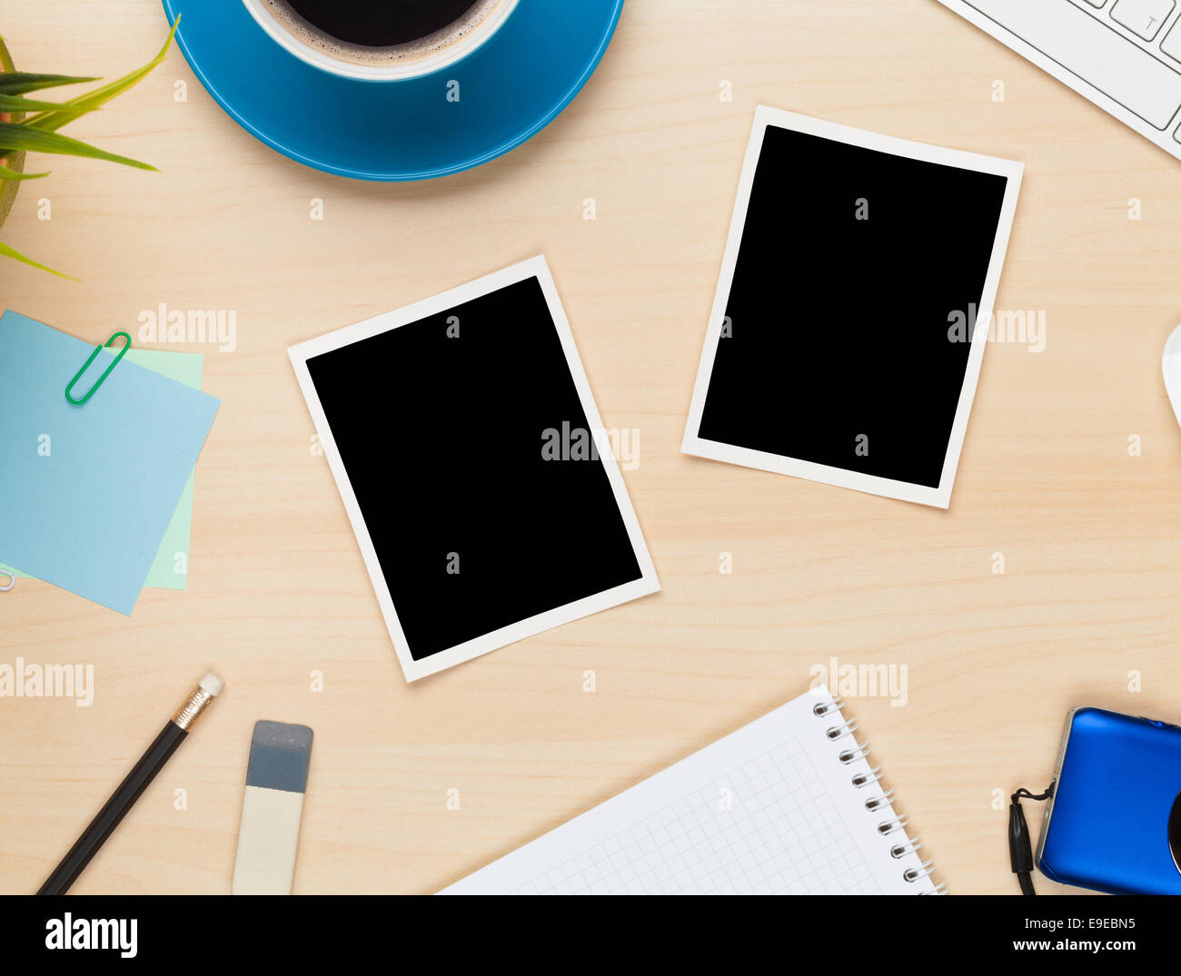 Photo frames on office table with notepad, computer and camera. View
