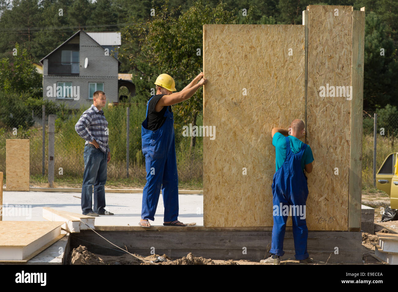 Team of young builders erecting prefabricated wall panels on a building site of a new house Stock Photo