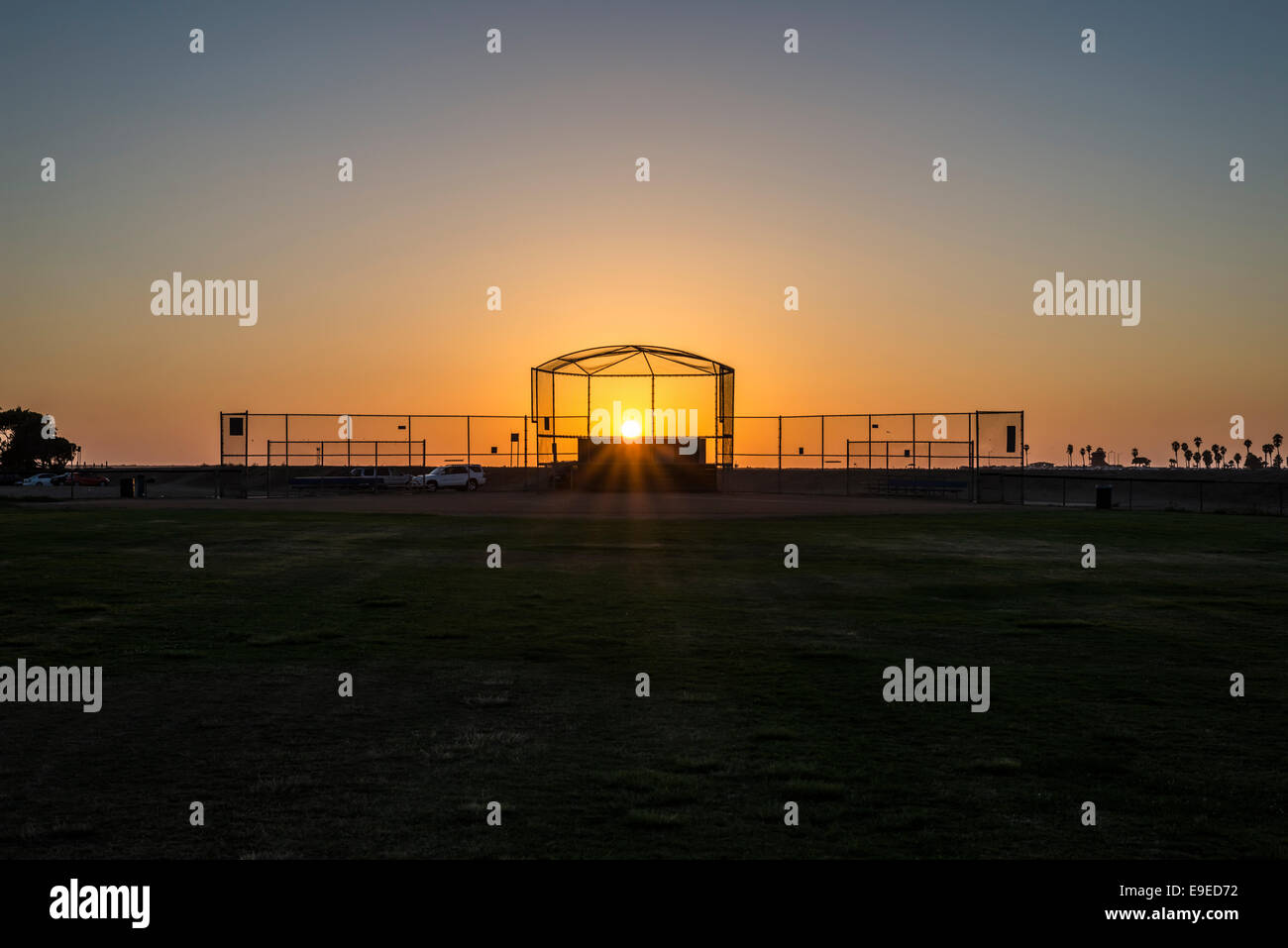 The Sun setting through a chain link fence at Robb Field. San Diego, California, United States. Stock Photo