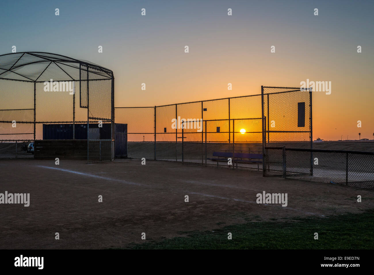 The Sun setting through a chain link fence at Robb Field. San Diego, California, United States. Stock Photo