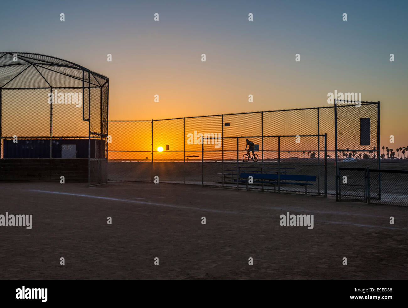 The Sun setting through a chain link fence at Robb Field. San Diego, California, United States. Stock Photo