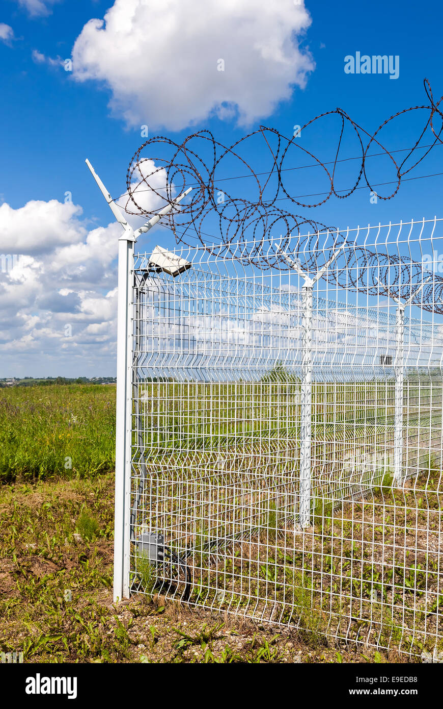 Fence with barbed wire on blue sky background Stock Photo - Alamy