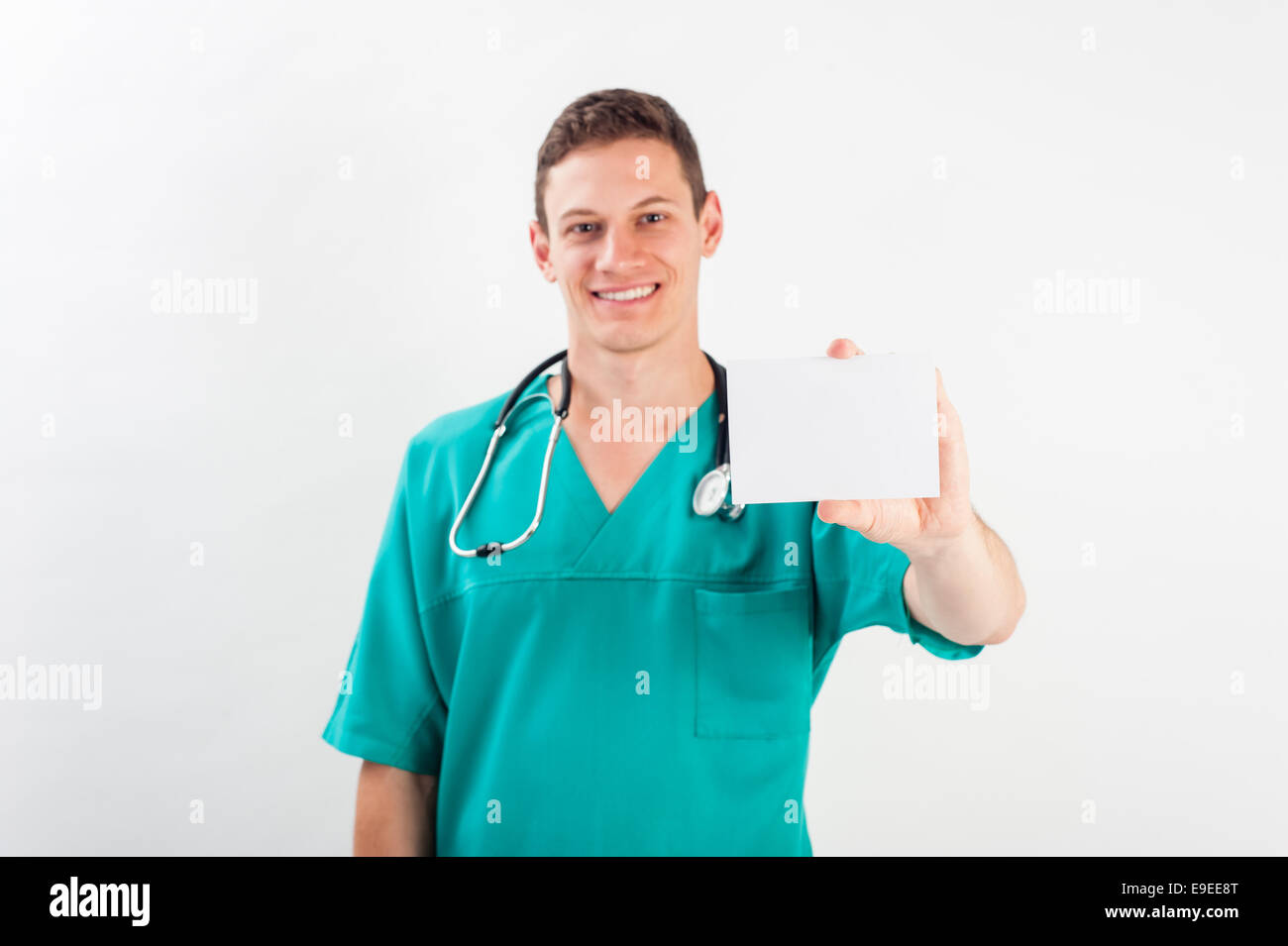 Medical portrait. Male nurse or young man doctor smiling happy and proud in blue scrubs isolated on white background. Young caucasian male medical pro Stock Photo