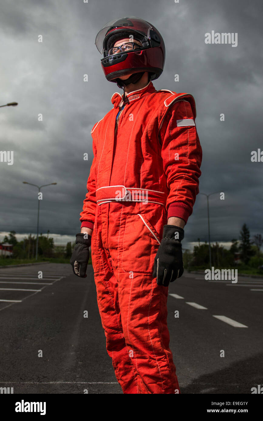 Racer posing with his arms crossed wearing red racing suit and helmet
