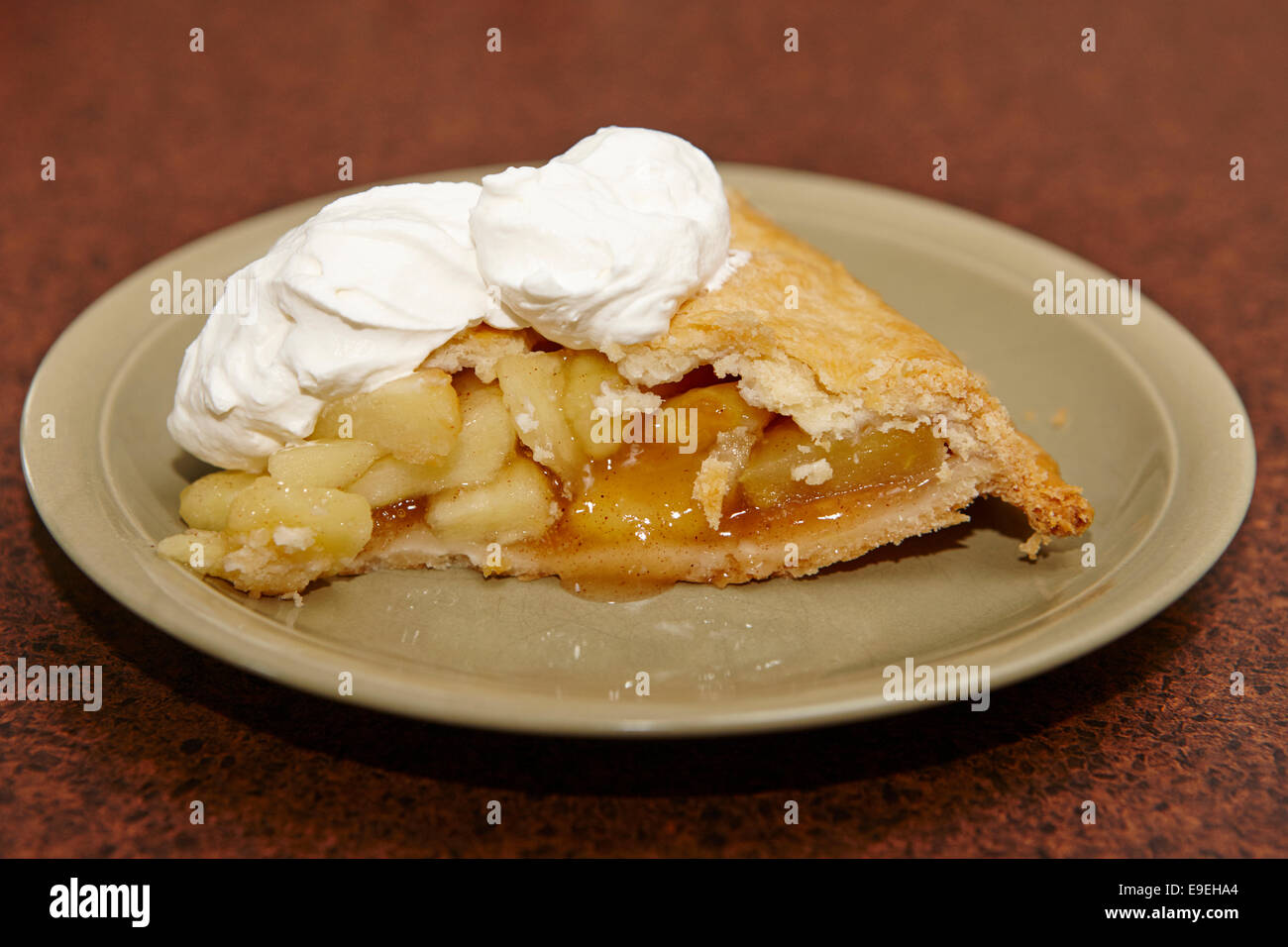 large slice of mass produced apple pie with whipped cream topping Stock Photo