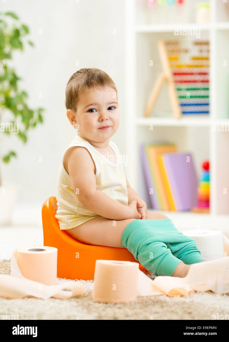 smiling child sitting on chamber pot with toilet paper Stock Photo
