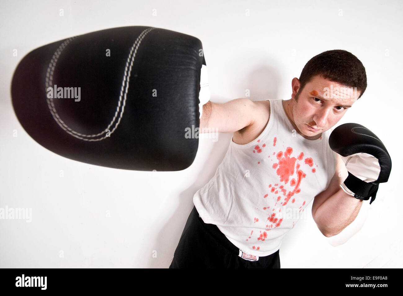 a man in a boxing pose hits out towards the camera with blood soaked top Stock Photo