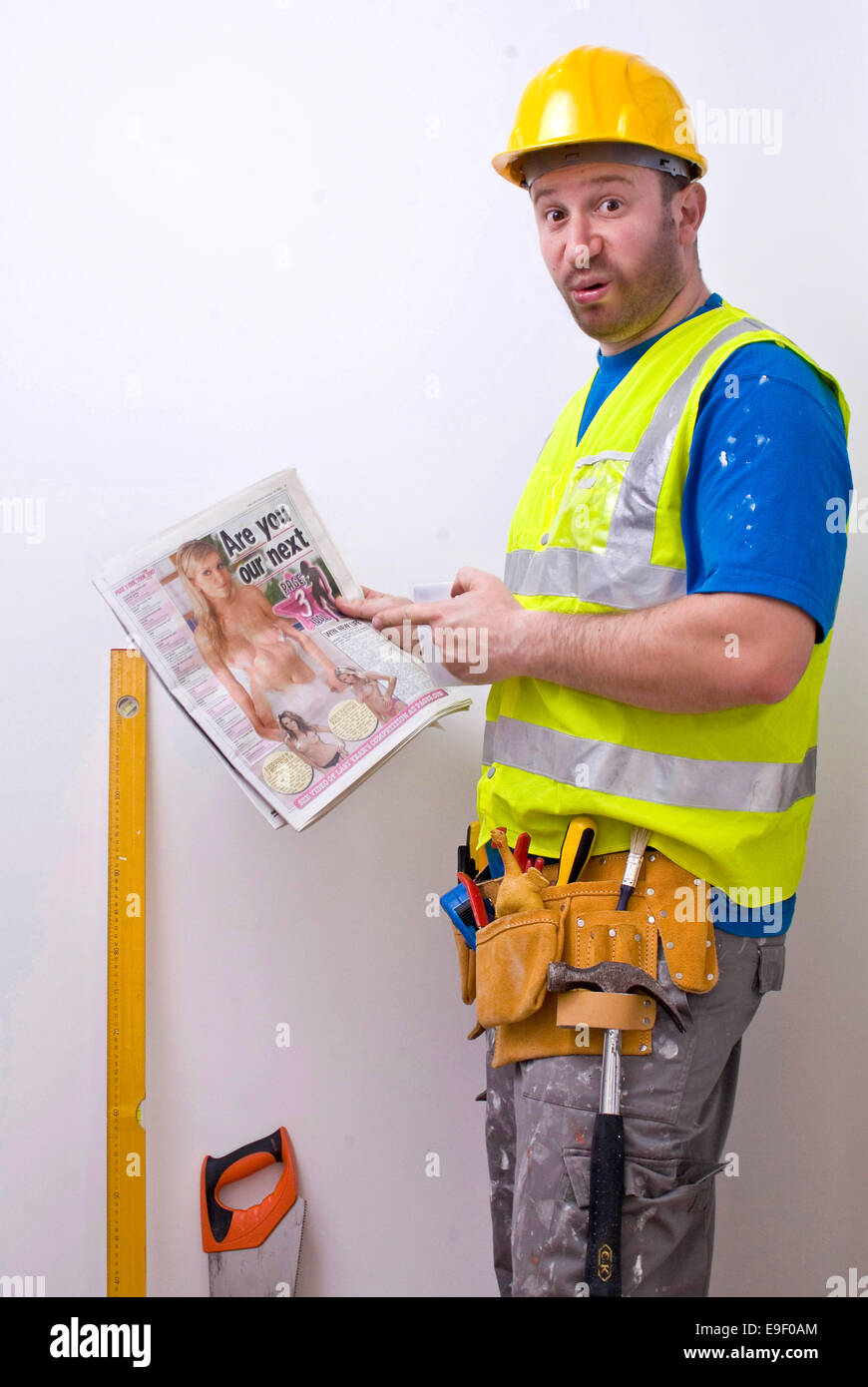 a man dressed as a builder looks at page three in the sun, Stock Photo