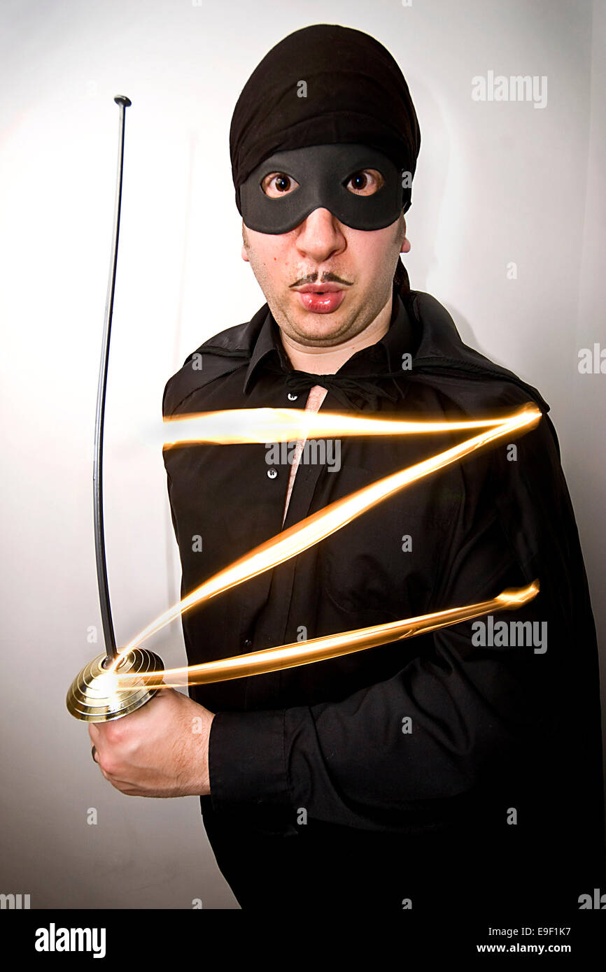 a man dressed in a funny mask of zorro outfit, with a sword, Stock Photo