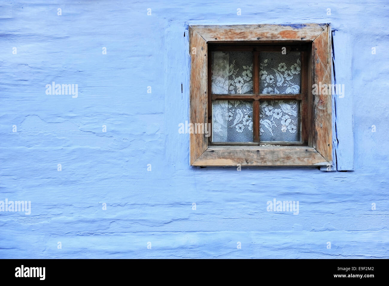Architecture detail with old wooden window on a blue wall of an adobe house Stock Photo