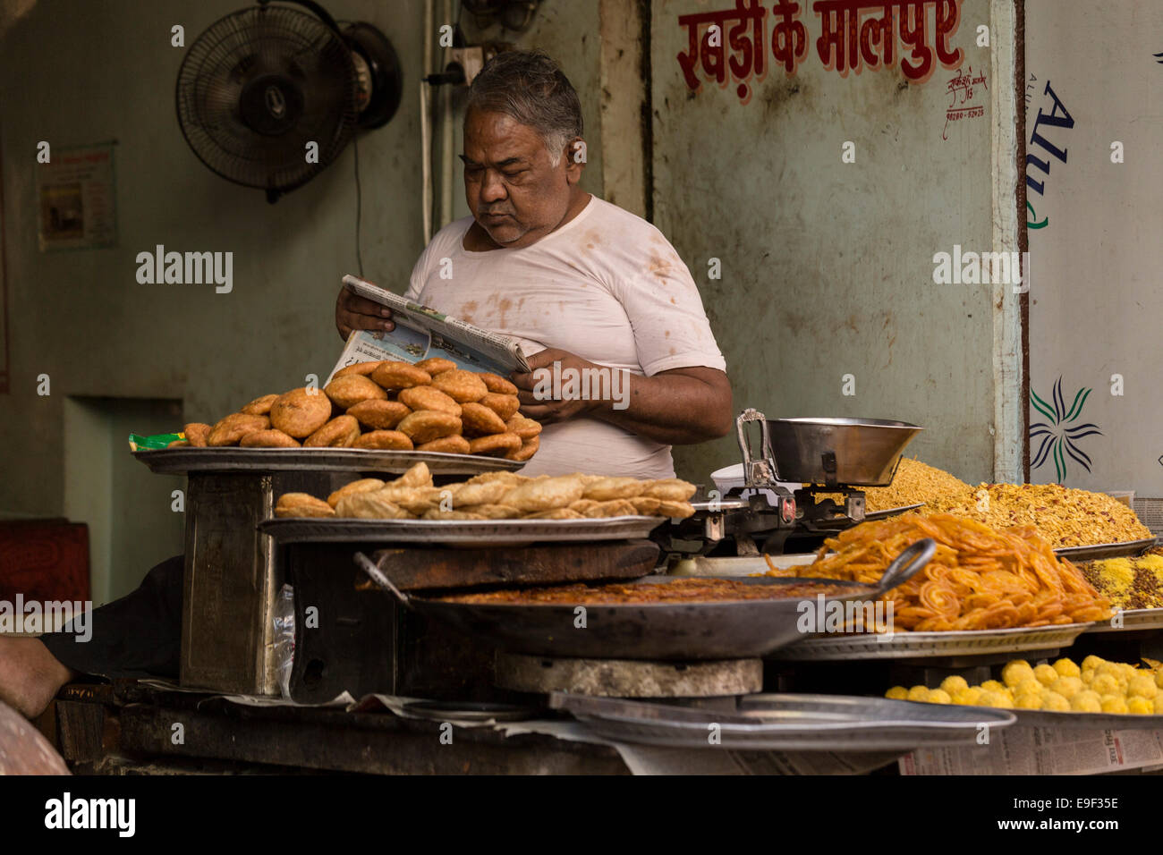 Sweet vendor reading a newspaper. Sadar Bazaar, Pushkar, Rajasthan, India Stock Photo