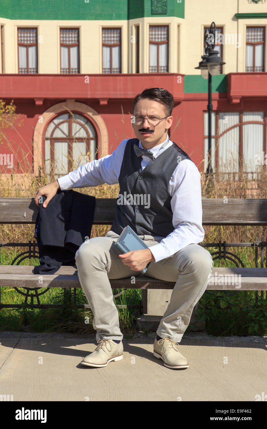 Businessman with a book sitting on the bench in front of old building ...