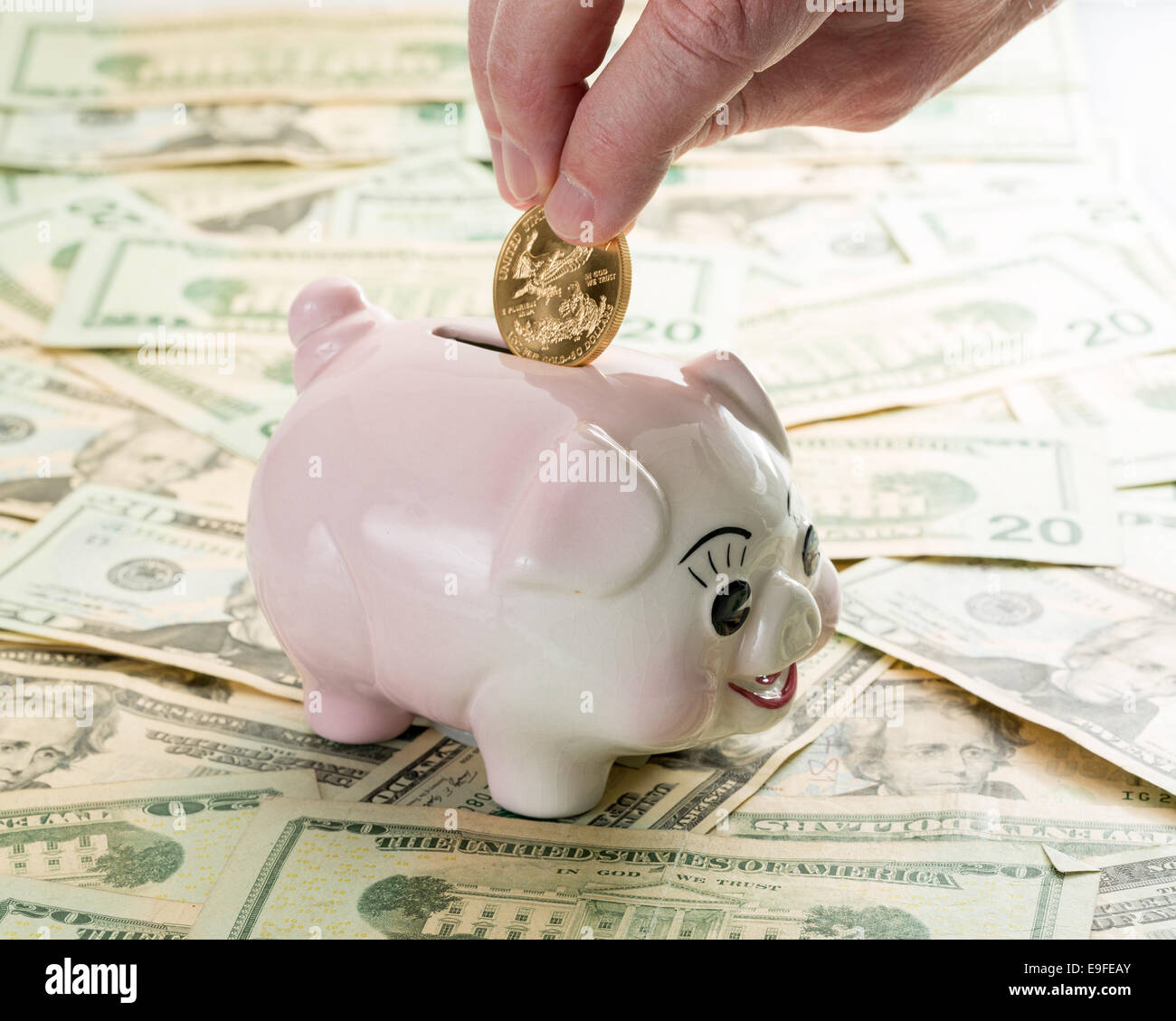 Hand placing gold coin into piggy bank Stock Photo - Alamy