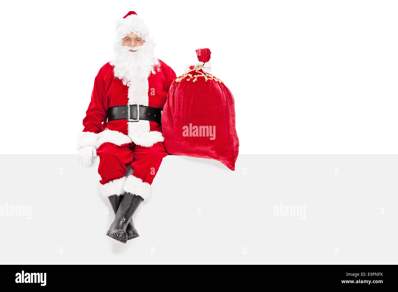 Santa holding a bag of presents seated on a panel isolated on white ...