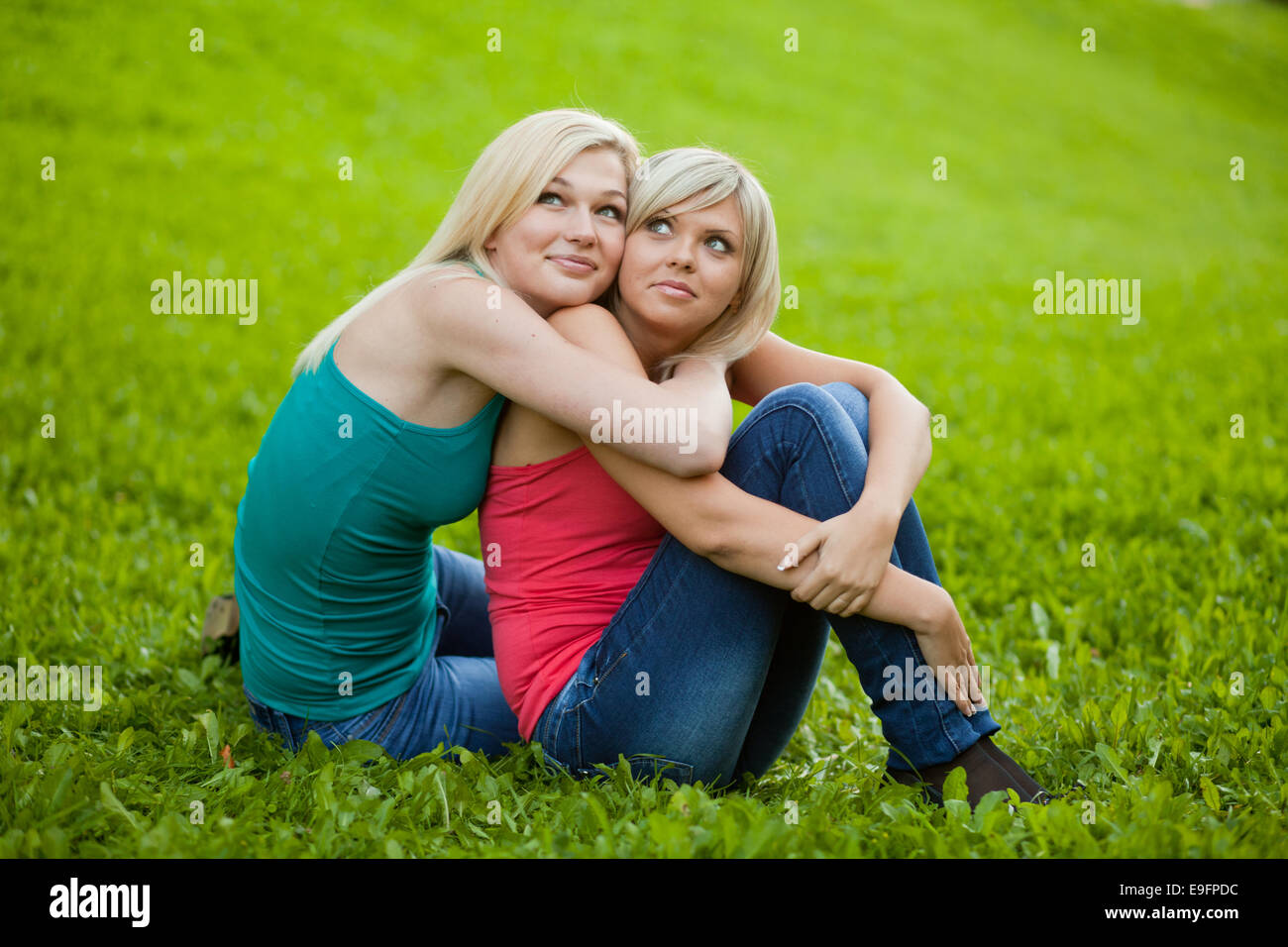Two girls sitting on the grass, embracing Stock Photo - Alamy