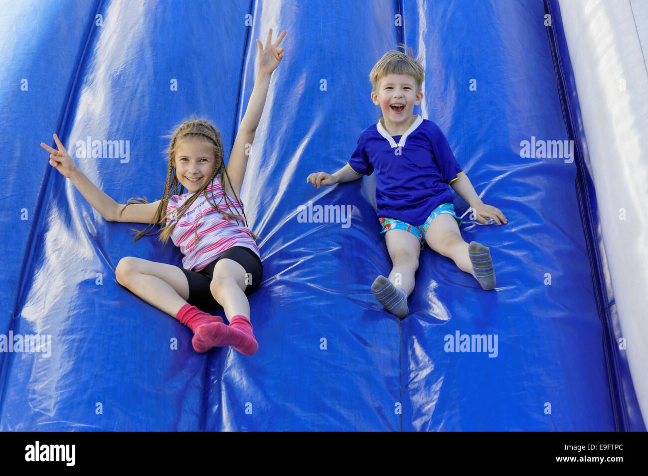 Funny kids and off the inflatable slides Stock Photo