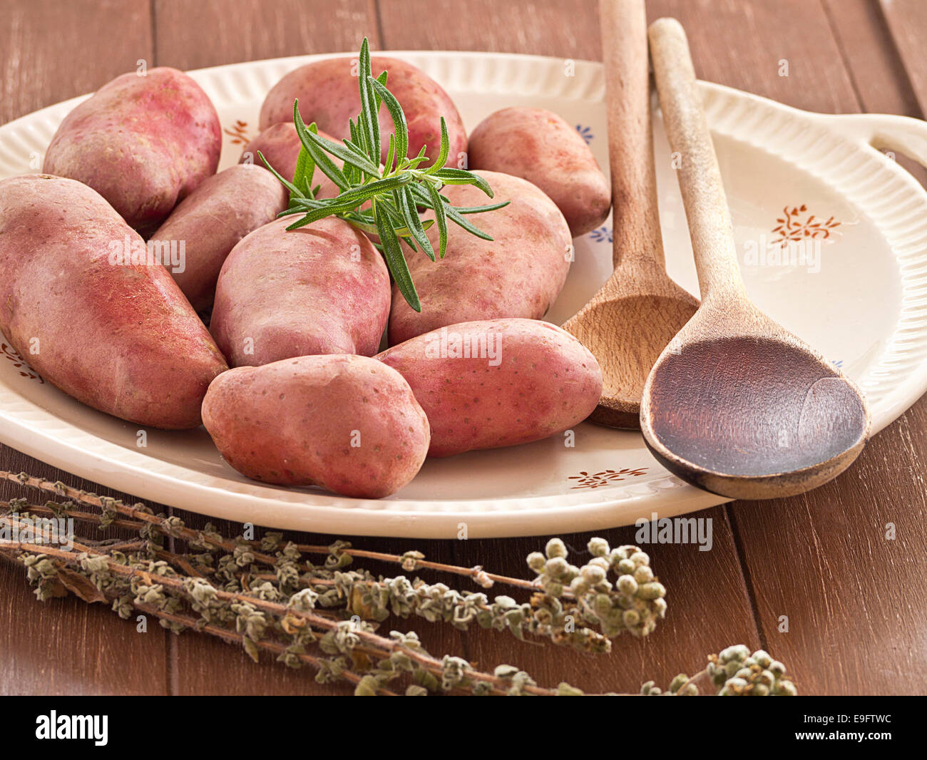 Uncooked potatoes with herbs on a plate Stock Photo