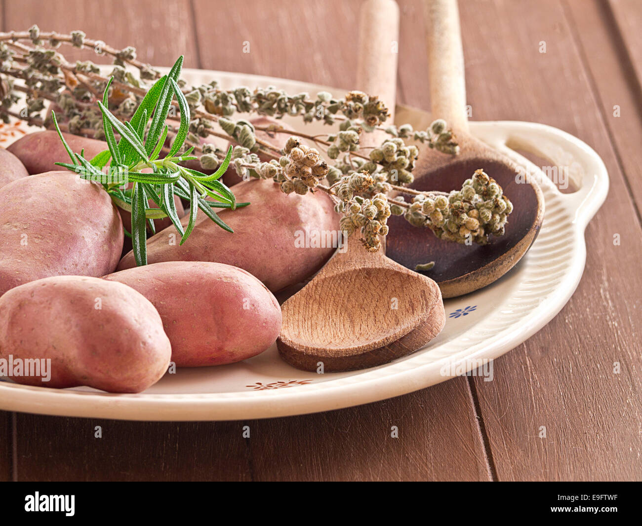 Uncooked potatoes with herbs on a plate Stock Photo