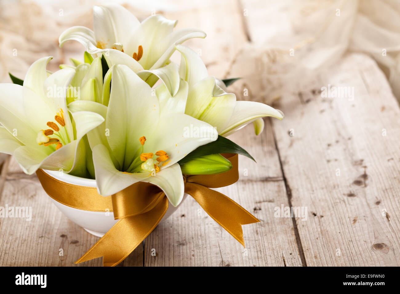Closeup shot of white lilies on wooden table. Stock Photo