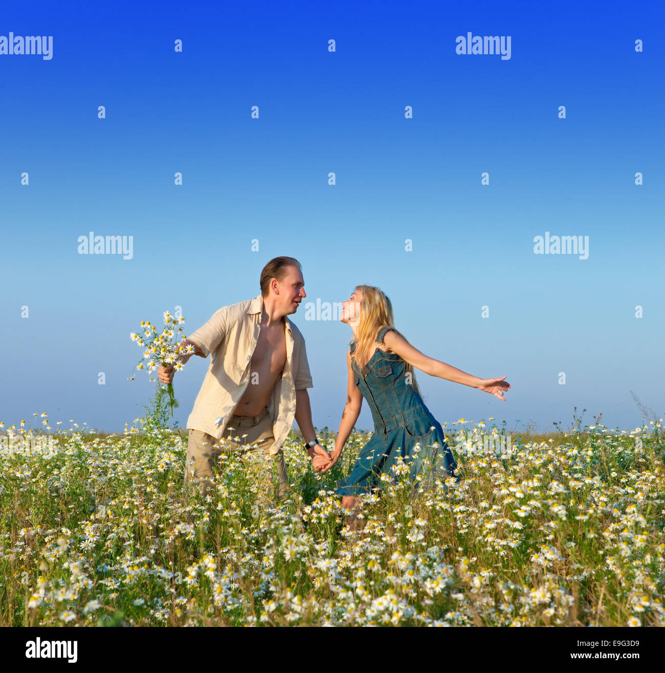 happy young pair in the field of chamomiles Stock Photo