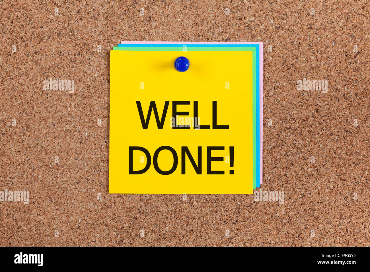 Post-it notes with word 'Well done!' on cork board (bulletin board). Stock Photo