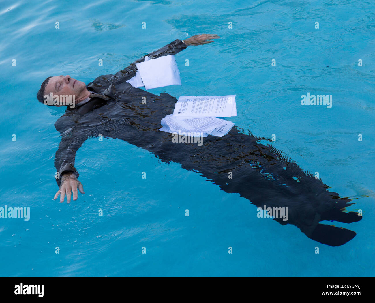 Senior man floating among papers in water Stock Photo