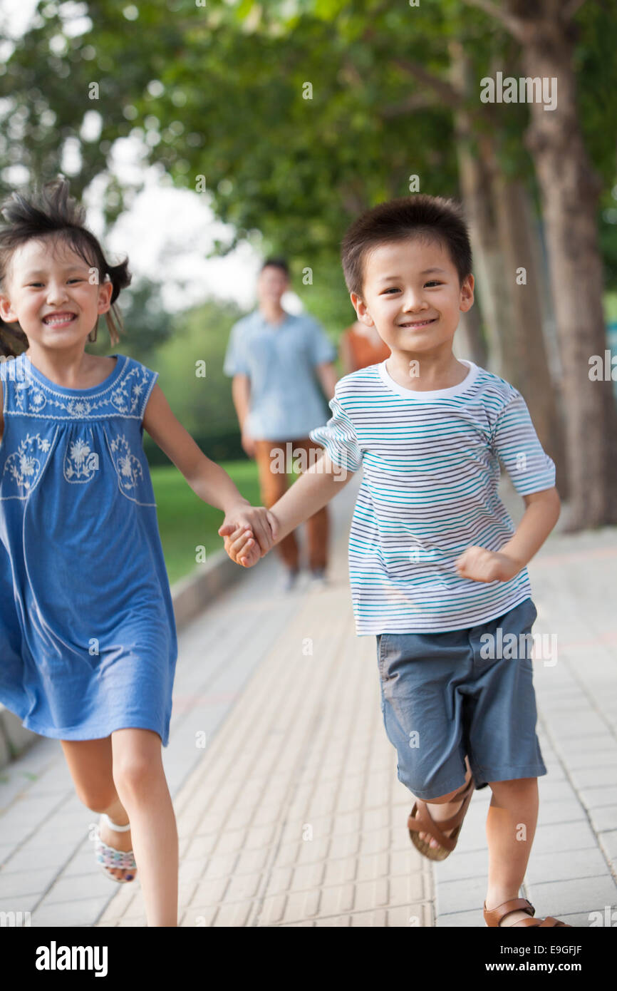 Happy brother and sister holding hands running Stock Photo - Alamy