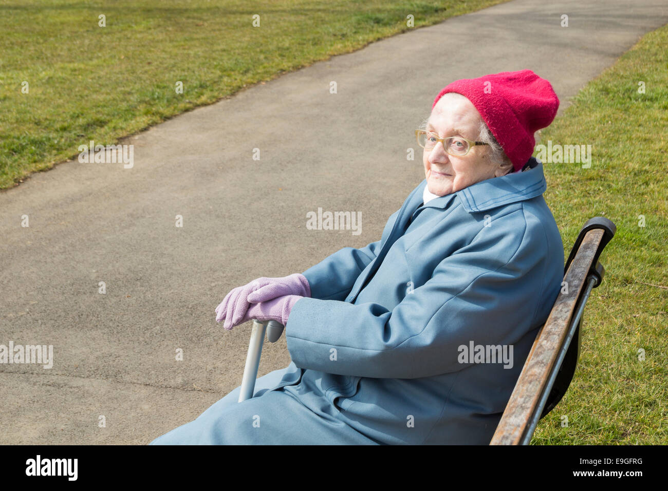Ninety year old lady sitting on park bench in Autumn. England. UK Stock Photo