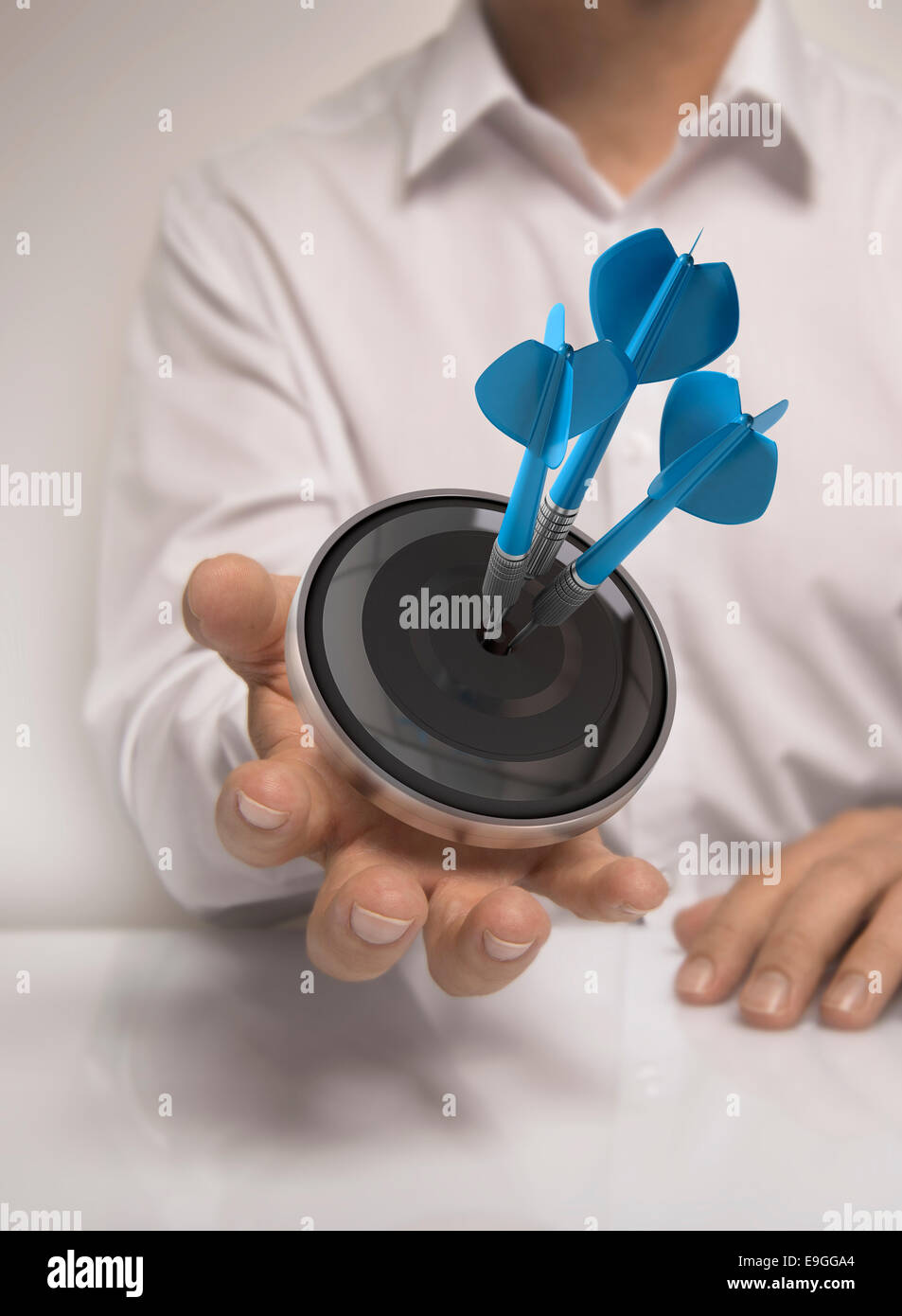 Man hand holding a target with three darts hitting the center, blue and beige tones, concept image for illustration of marketing Stock Photo