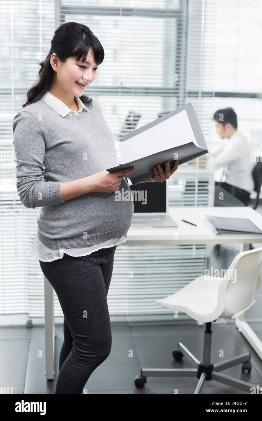 Pregnant businesswoman holding portfolios Stock Photo