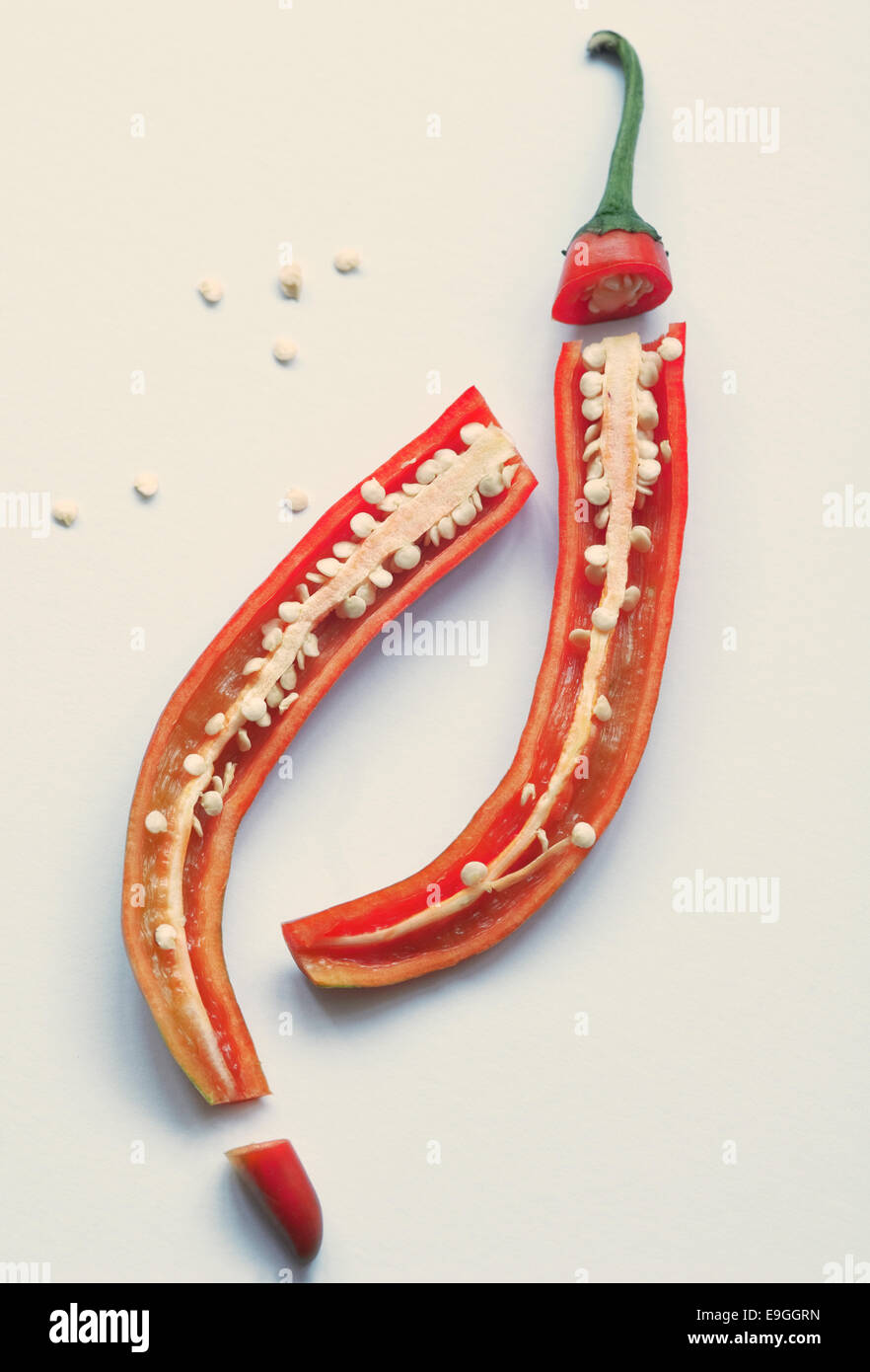 Still life food image of a red chilli pepper sliced open to show seeds on a plain background Stock Photo