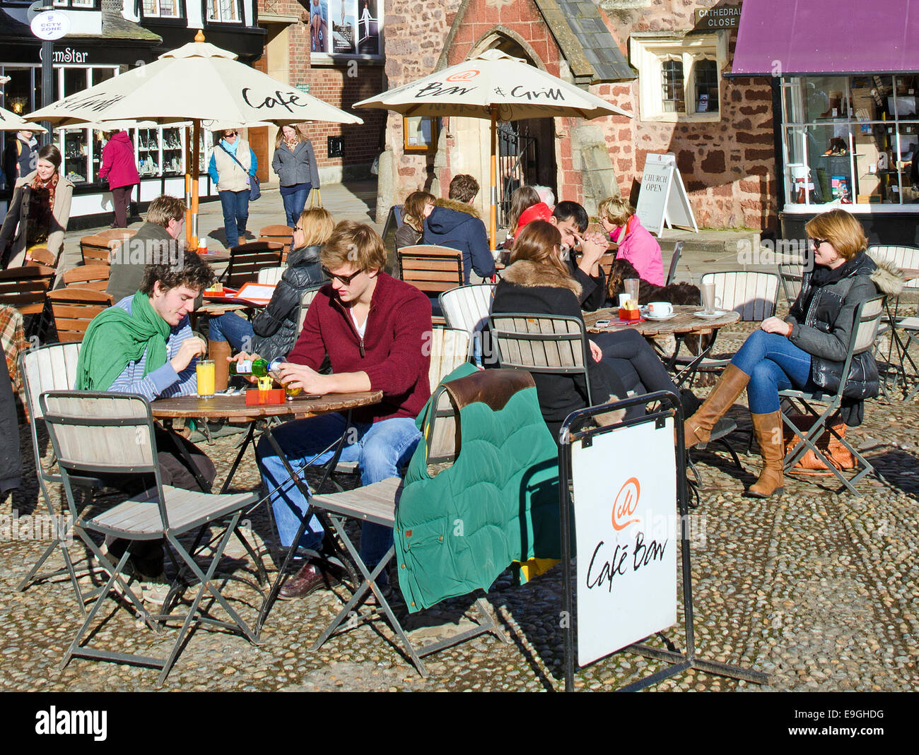 tourists on outside tables at a cafe in cathedral square, exeter, devon, uk Stock Photo