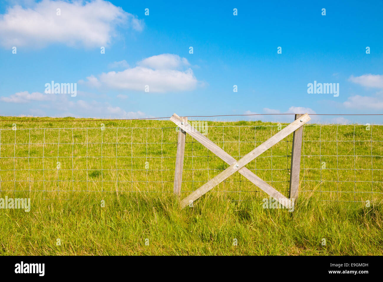 Fencing at grassy dike and blue sky with clouds Stock Photo Alamy