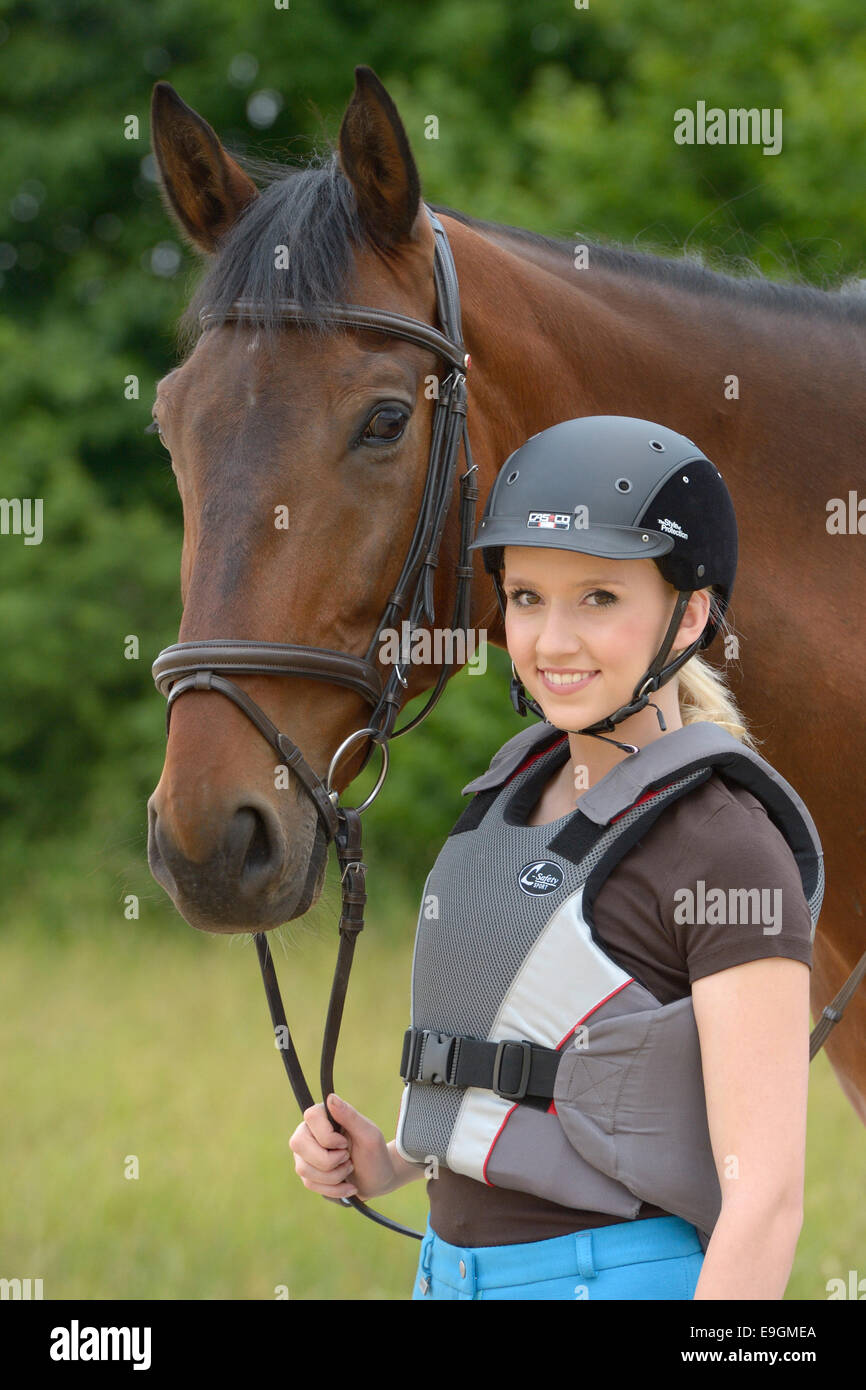 Teen rider wearing a helmt and a body protector and her Bavarian horse Stock Photo