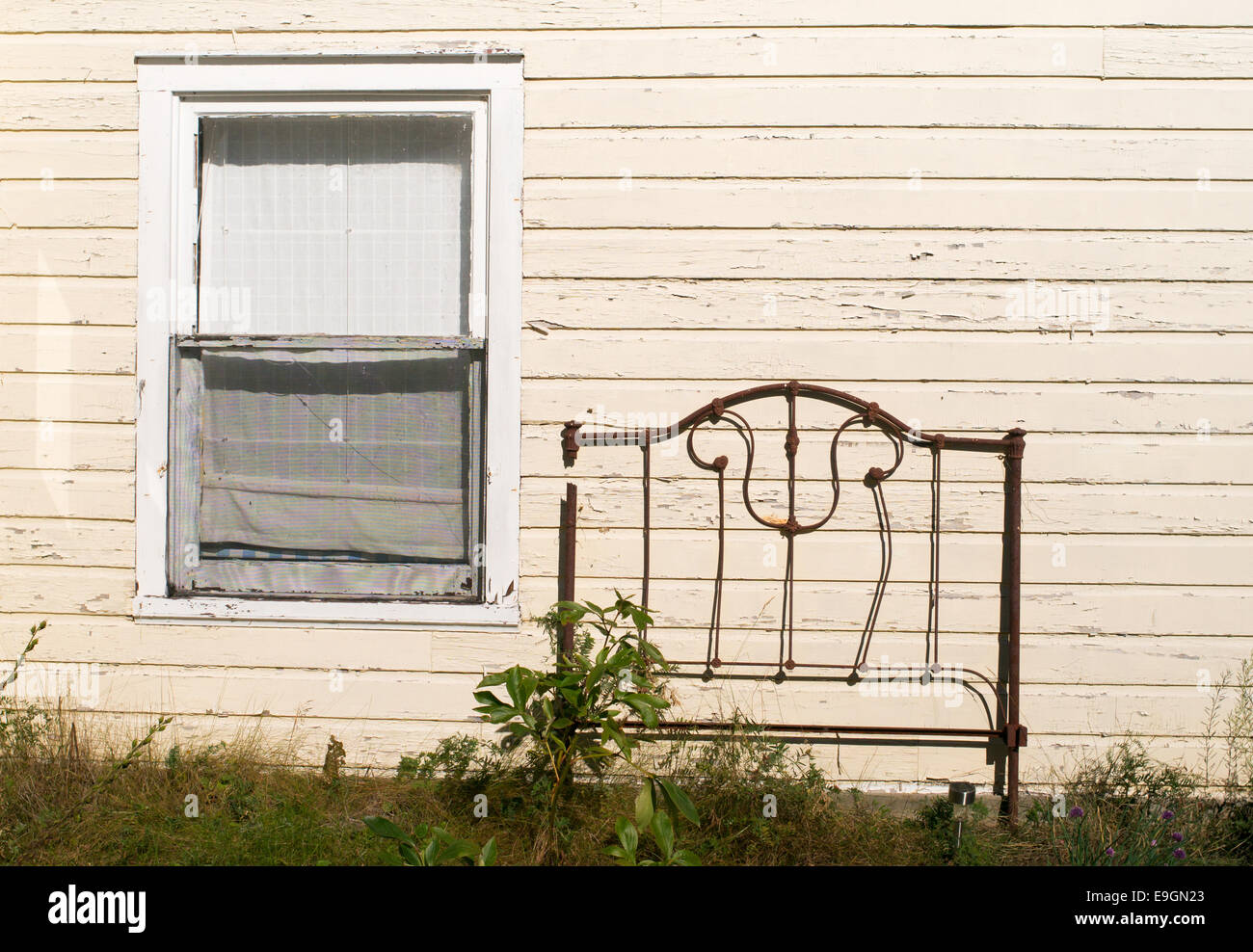 An old rusty bedhead lies against a wooden house in Silver Islet, Ontario, Canada Stock Photo