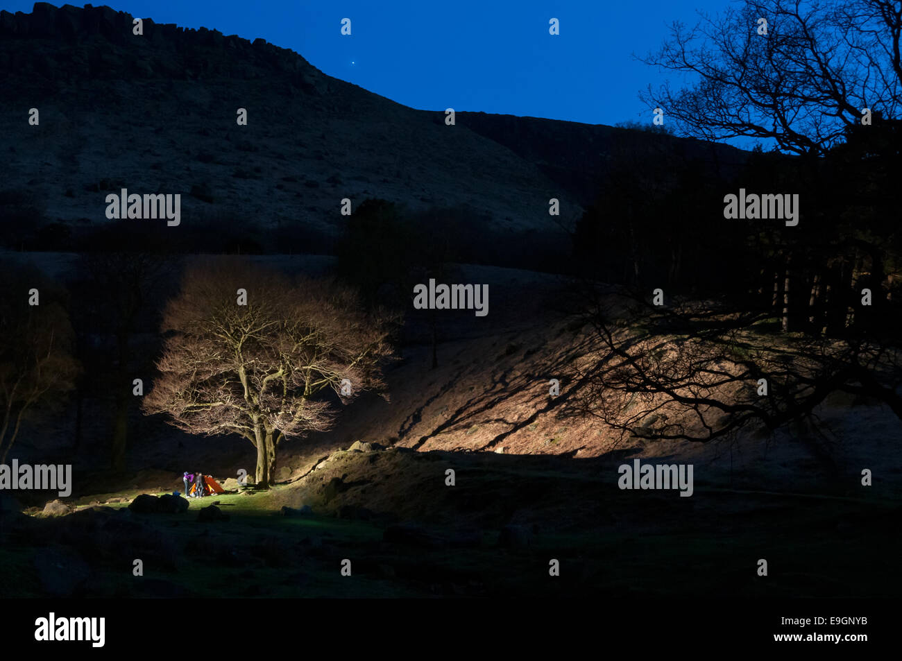 Friends setting up tent for camping in the night at the Peak District, UK Stock Photo