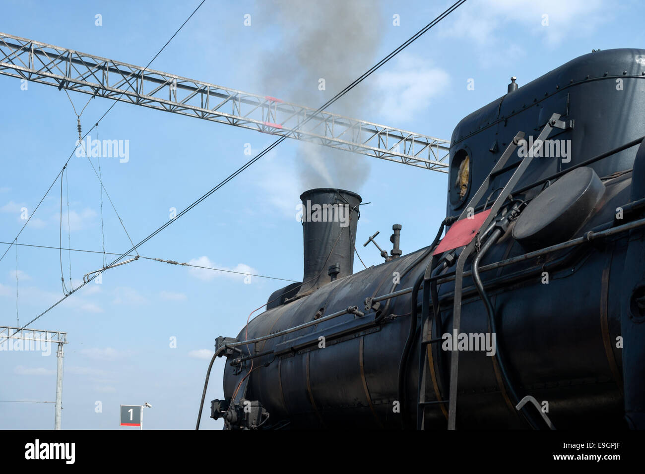 Steam locomotive in steam and ready to depart. Partial view of black boiler and chimney. Smoke comes out of a chimney Stock Photo