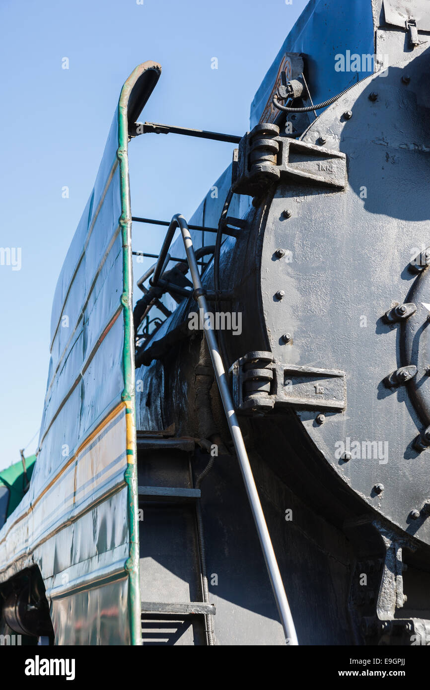 Partial view of a steam locomotive boiler of black color and green metal screen against the background of blue sky Stock Photo