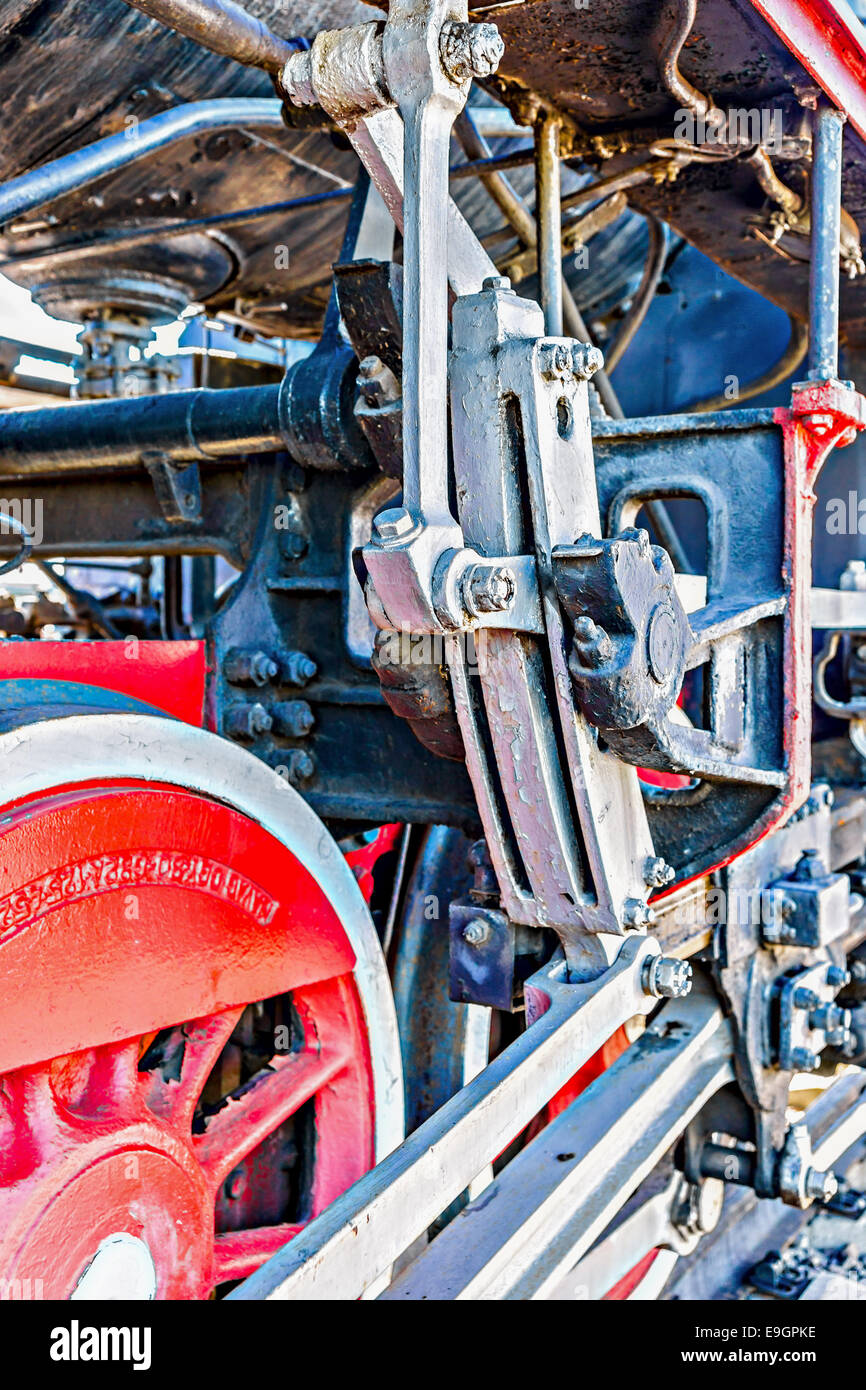 Closeup view of steam locomotive wheels, drives, rods, links and other mechanical details. White, black and red colors Stock Photo